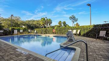 Una piscina al aire libre, sillones reclinables de piscina