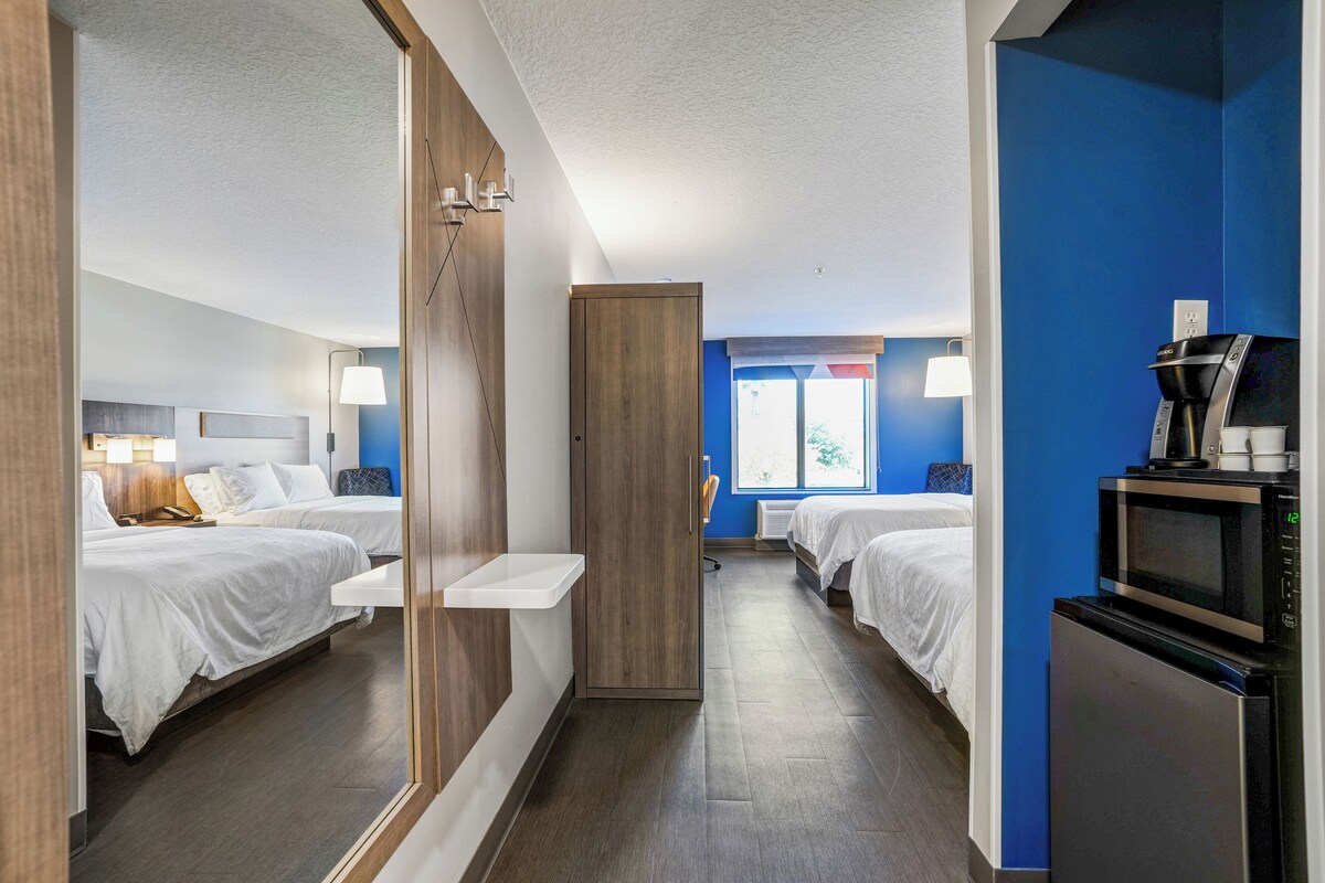 A hotel room with two beds, a microwave, a coffee maker, and a small sink.