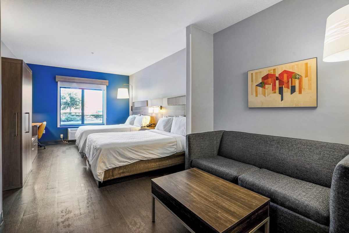 Een hotelkamer met een bed, een bank, een tafeltje, een raam en een schilderij aan de muur.
