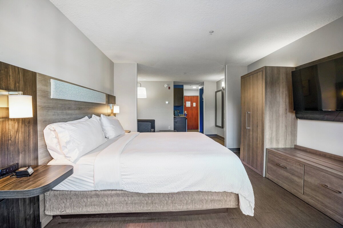 Una habitación de hotel con una cama grande, mesitas de noche, un televisor y un armario.