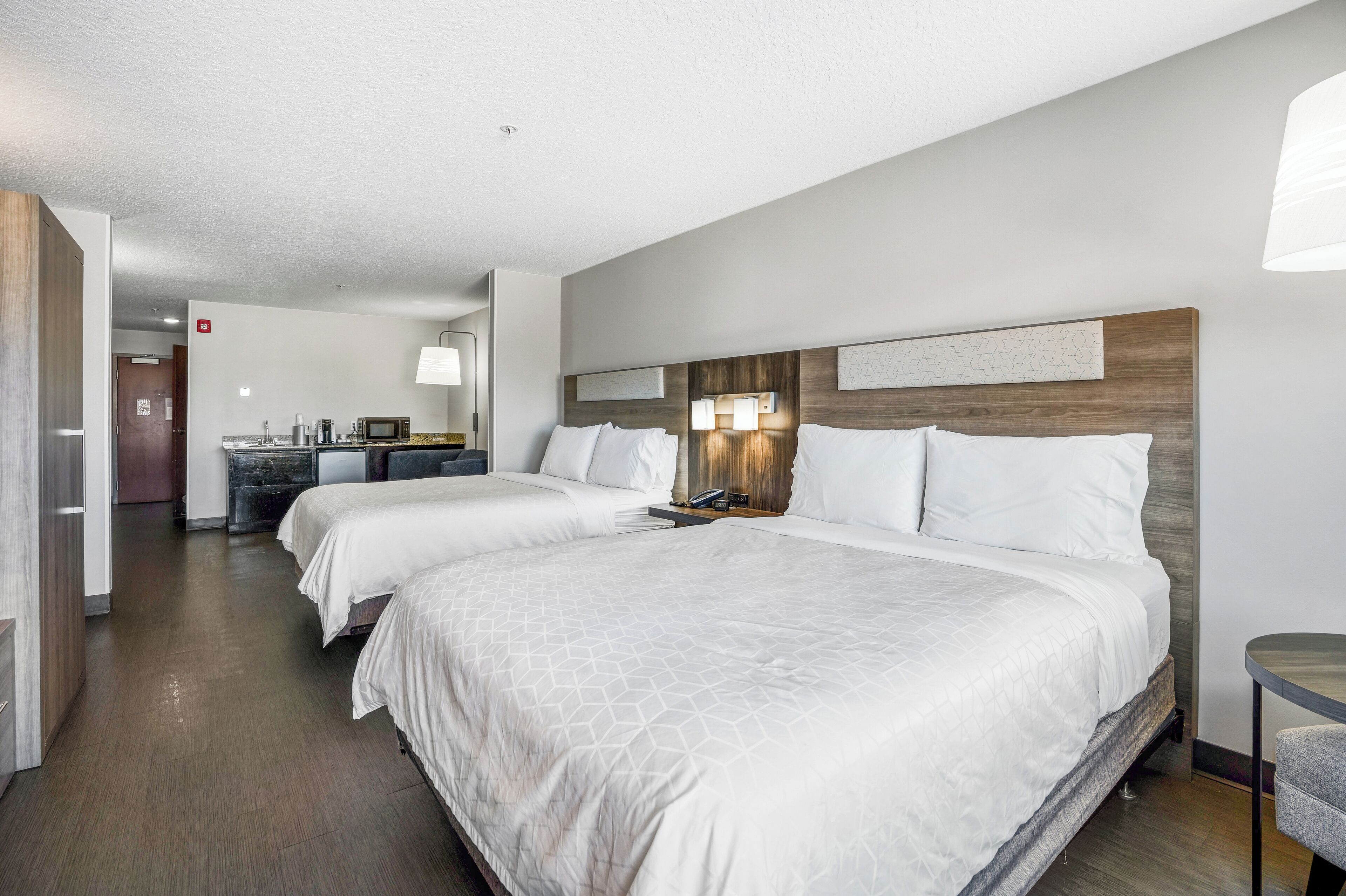 Een hotelkamer met twee bedden, een kitchenette en een eethoek.