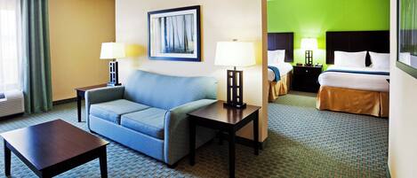 A hotel room with a sofa, a table, a bed, and a nightstand with lamps.