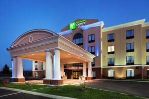 Un hotel Holiday Inn Express con entrada cubierta, varios pisos y una fachada bien iluminada.