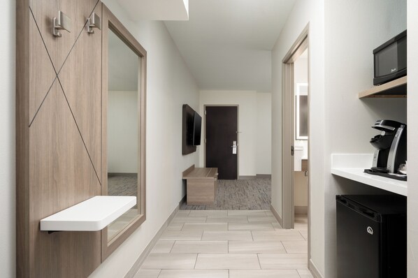 A modern hallway with a wooden wardrobe, a small white shelf, a flat-screen TV, a microwave, and a coffee machine. - Holiday Inn Express & Suites Newport S by IHG (Newport)