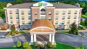 A Holiday Inn Express hotel with a central entrance, multiple floors, and a view of mountains in the background. - Holiday Inn Express & Suites Newport S by IHG (Newport)
