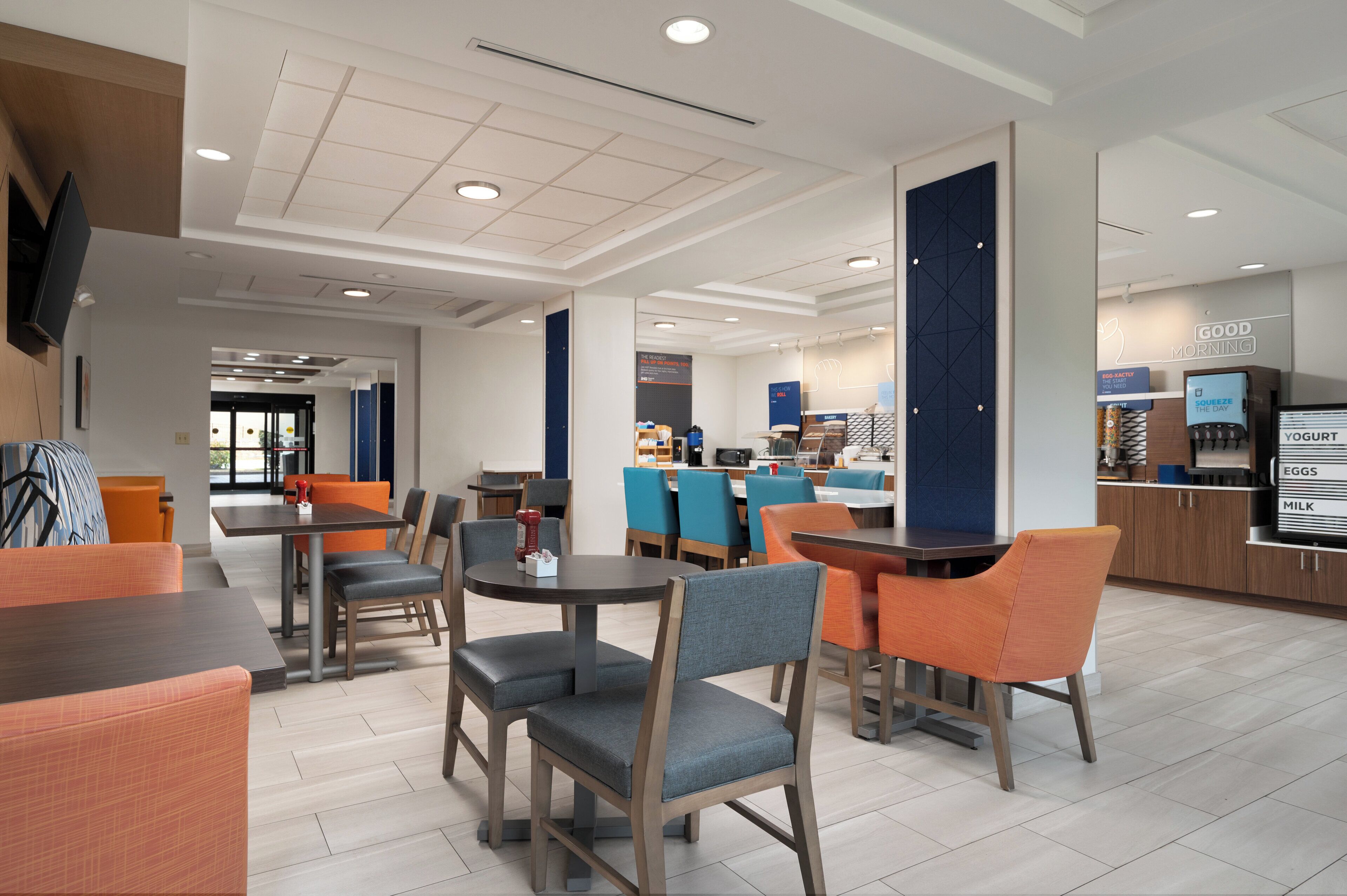 Un moderno vestíbulo de hotel con zonas de estar, un mostrador de recepción y una barra de comida.