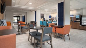 A modern hotel lobby with seating areas, a reception desk, and a food counter. - Holiday Inn Express & Suites Newport S by IHG (Newport)