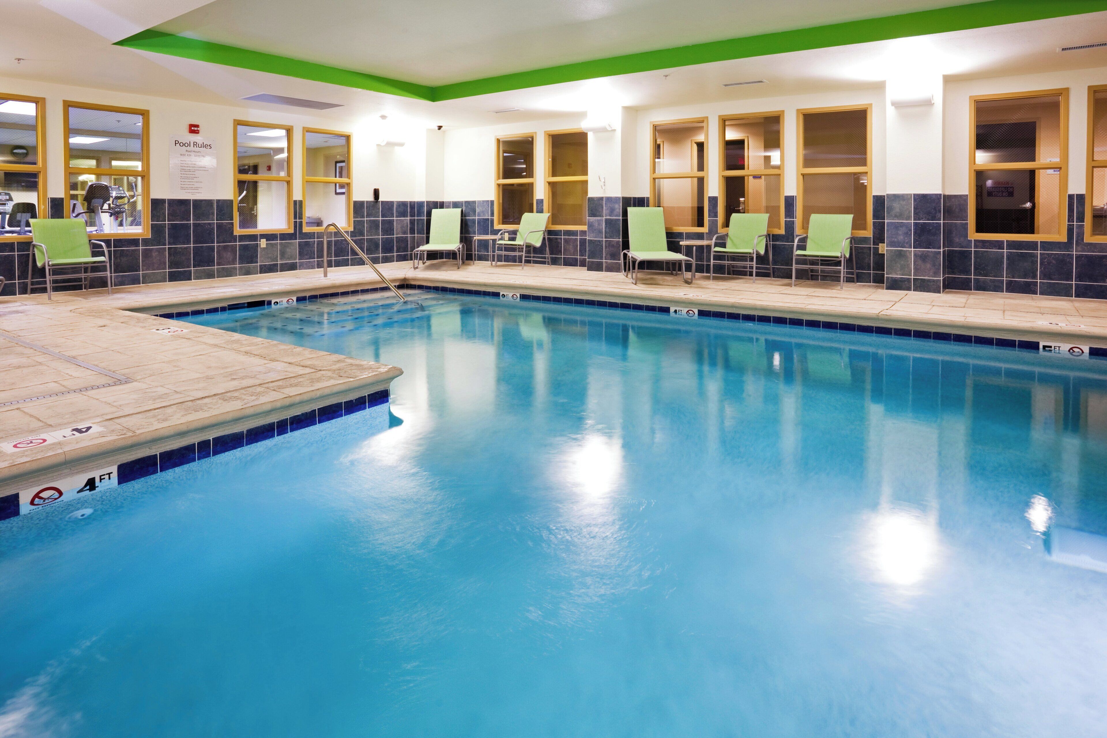A swimming pool with a tiled deck and lounge chairs.