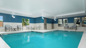 A swimming pool with a blue and white tiled wall, a few chairs, and a door leading to another room. - Holiday Inn Express & Suites Newport S by IHG (Newport)
