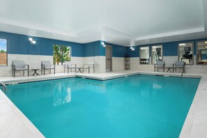 A swimming pool with a blue and white tiled wall, a few chairs, and a door leading to another room. - Holiday Inn Express & Suites Newport S by IHG (Newport)