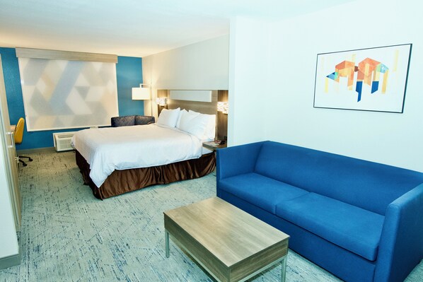 Een hotelkamer met een bed, een blauwe bank, een tafeltje en een kunstwerk aan de muur.