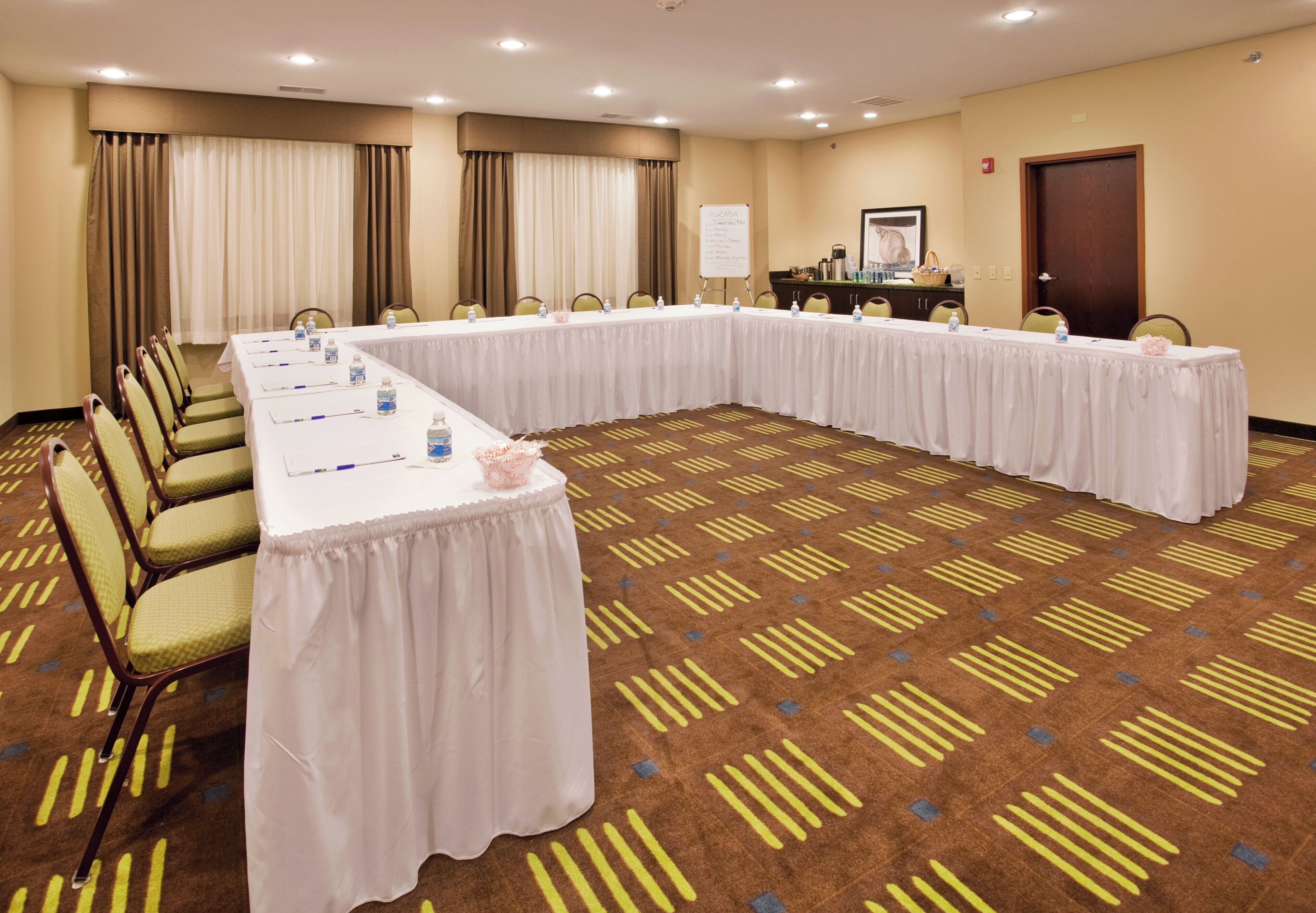 Un salón de conferencias con una mesa larga, sillas y una pizarra.
