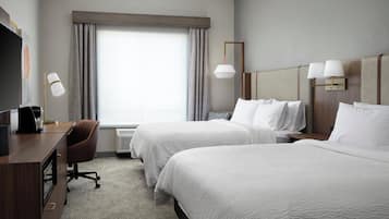 Habitación de hotel con dos camas, un escritorio, una silla y un televisor.