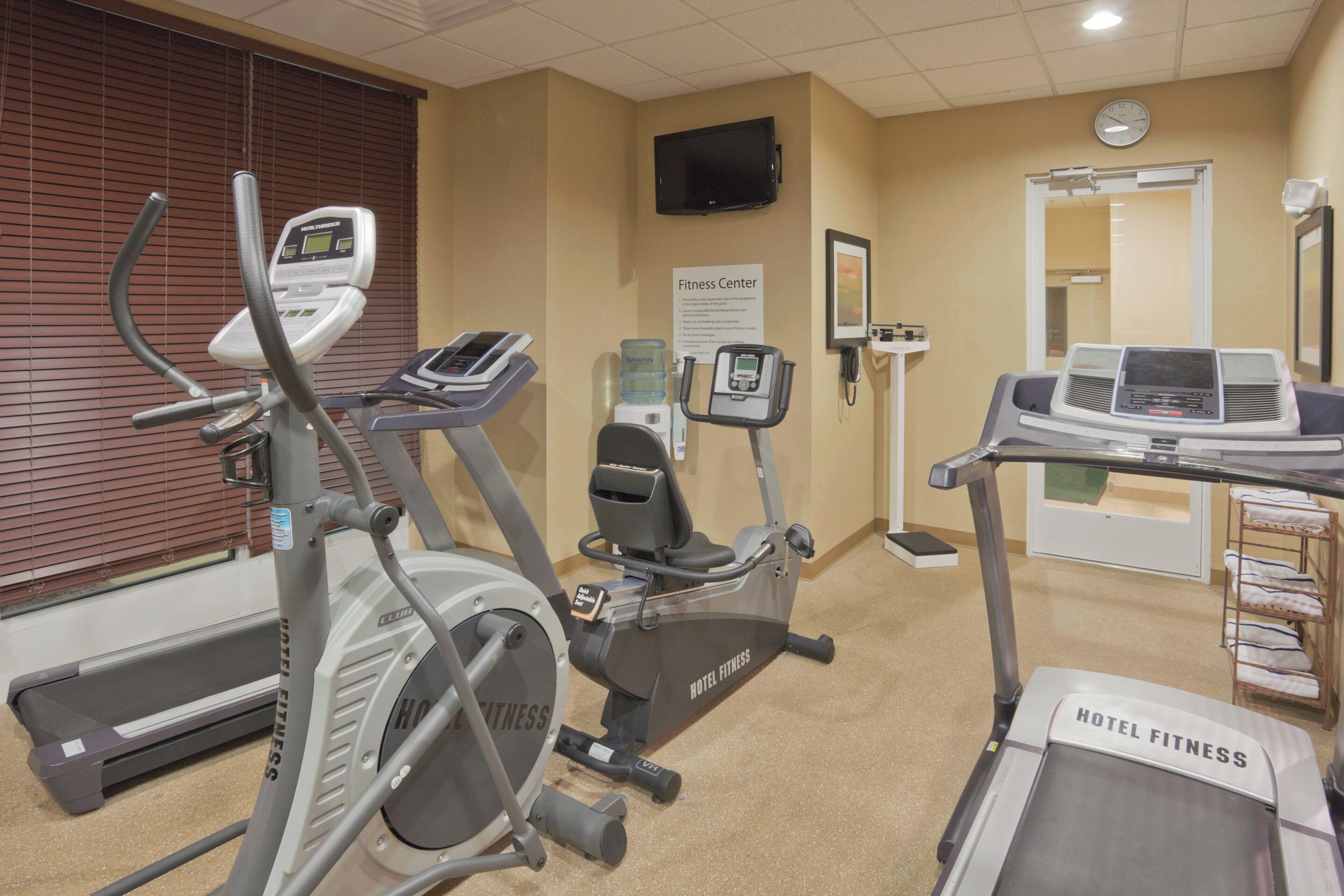 Un gimnasio con cintas de correr, elípticas y una bicicleta estática.