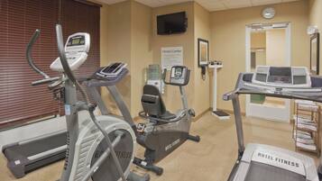 Un gimnasio con cintas de correr, elípticas y una bicicleta estática.