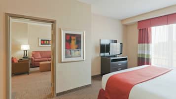 A hotel room with a bed, a television, a desk, a chair, a sofa, and a painting on the wall.