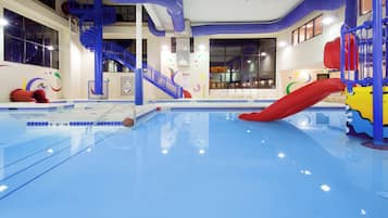 An indoor swimming pool with a blue floor, a red slide, and a blue staircase.