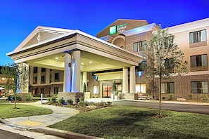 Un hôtel Holiday Inn Express & Suites doté d’un espace extérieur couvert, d’une façade en briques et d’un aménagement paysager soigné.