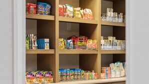 A pantry with shelves stocked with various food items and a wooden cabinet with drawers.