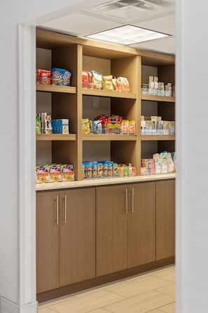 A pantry with shelves stocked with various food items and a wooden cabinet with drawers.