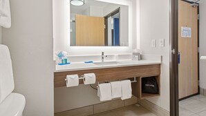 A modern bathroom with a white sink, wooden vanity, and a large mirror.