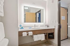 A modern bathroom with a white sink, wooden vanity, and a large mirror.