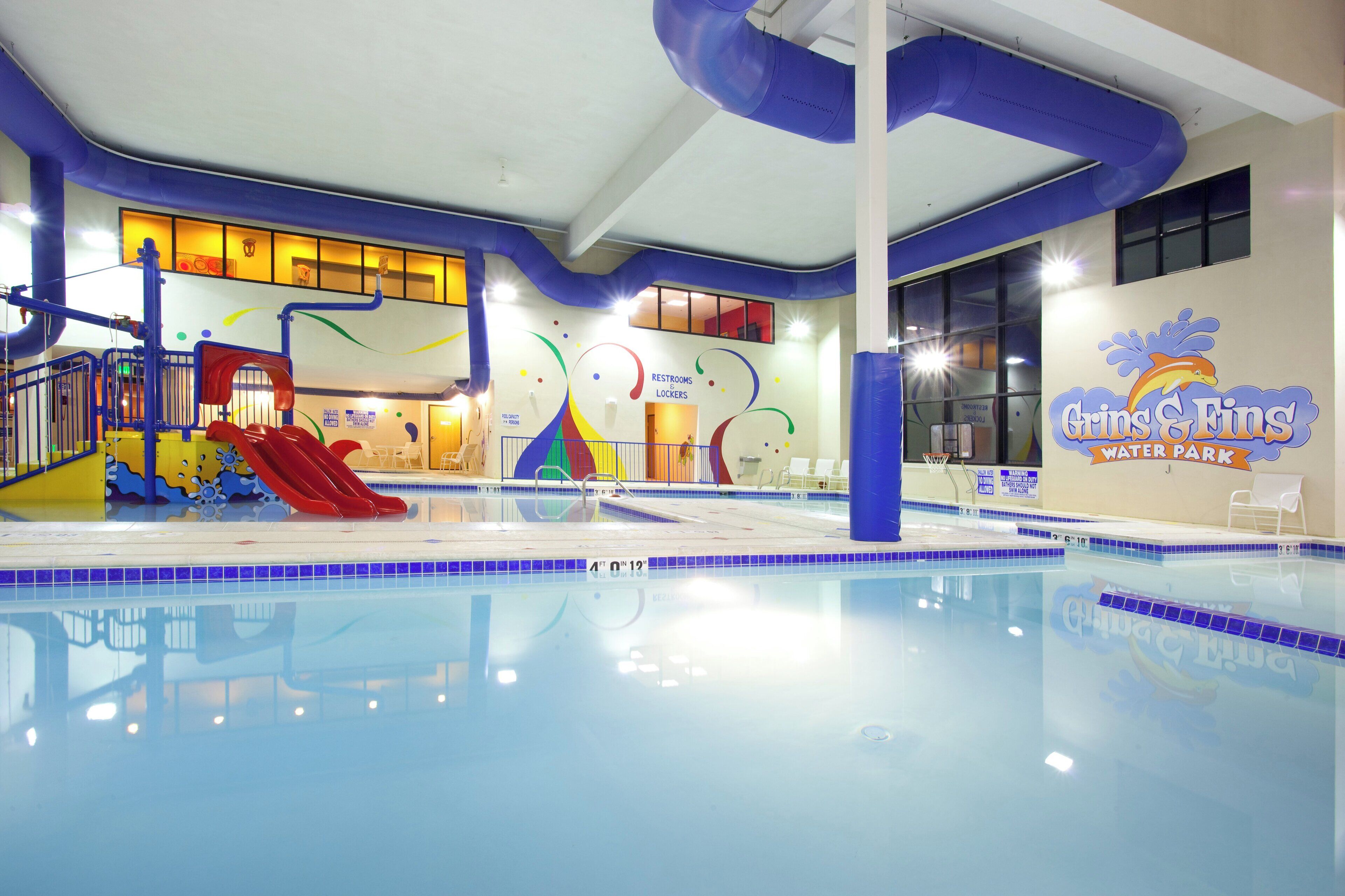 An indoor swimming pool with slides and a dolphin logo.