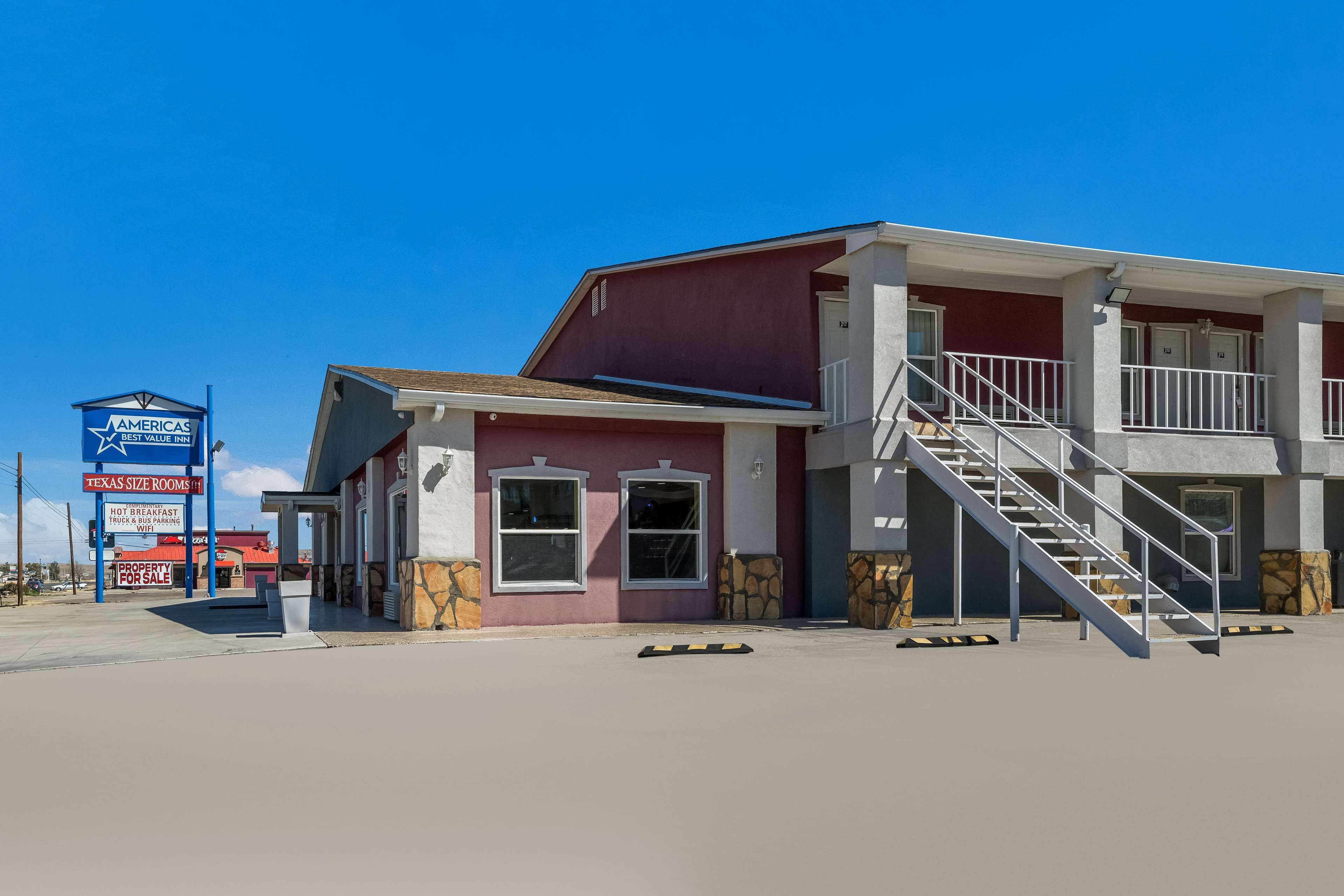 A two-story building with a red and white facade, a visible staircase, and a signboard advertising a Best Value Inn.
