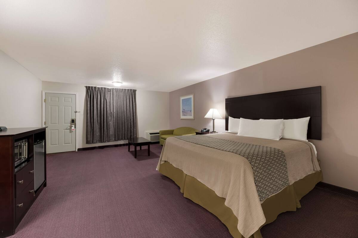 A hotel room with a bed, a desk, a chair, and a wardrobe.