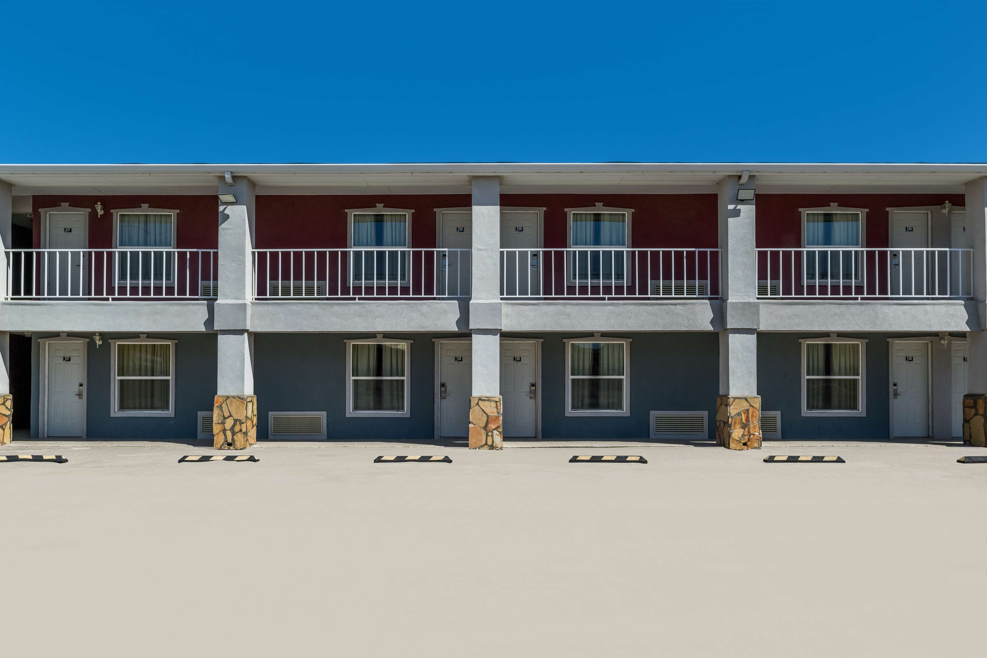 A row of three-story buildings with balconies, each featuring a door and windows.