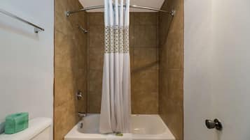 A bathroom with a bathtub, a shower curtain, and a toilet.