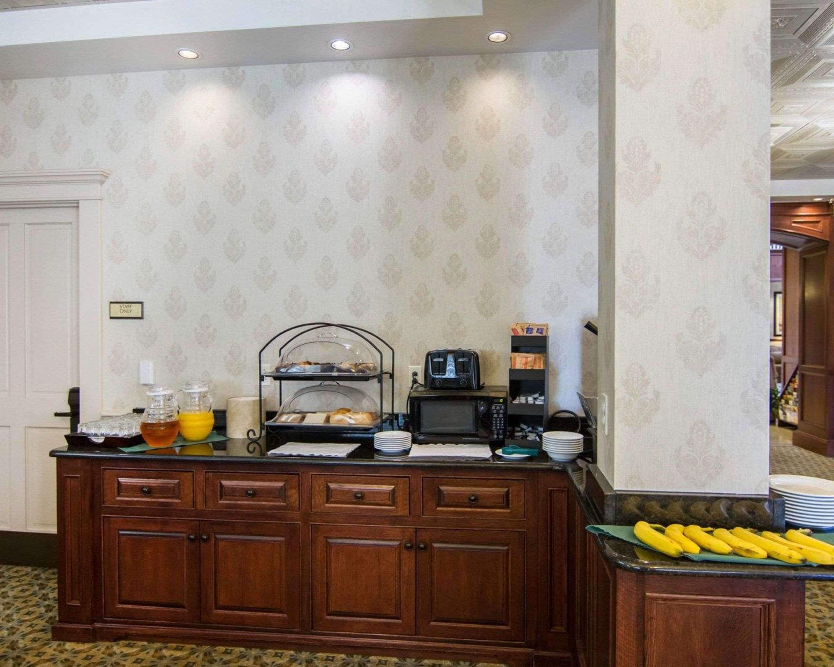 A buffet setup with a coffee maker, a microwave, and a fruit display.