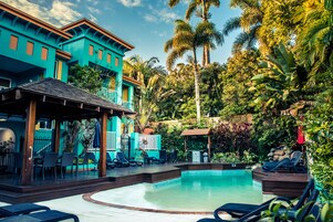 Una piscina al aire libre, sombrillas, sillones reclinables de piscina