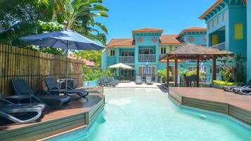 Een buitenzwembad, parasols bij het zwembad en ligstoelen