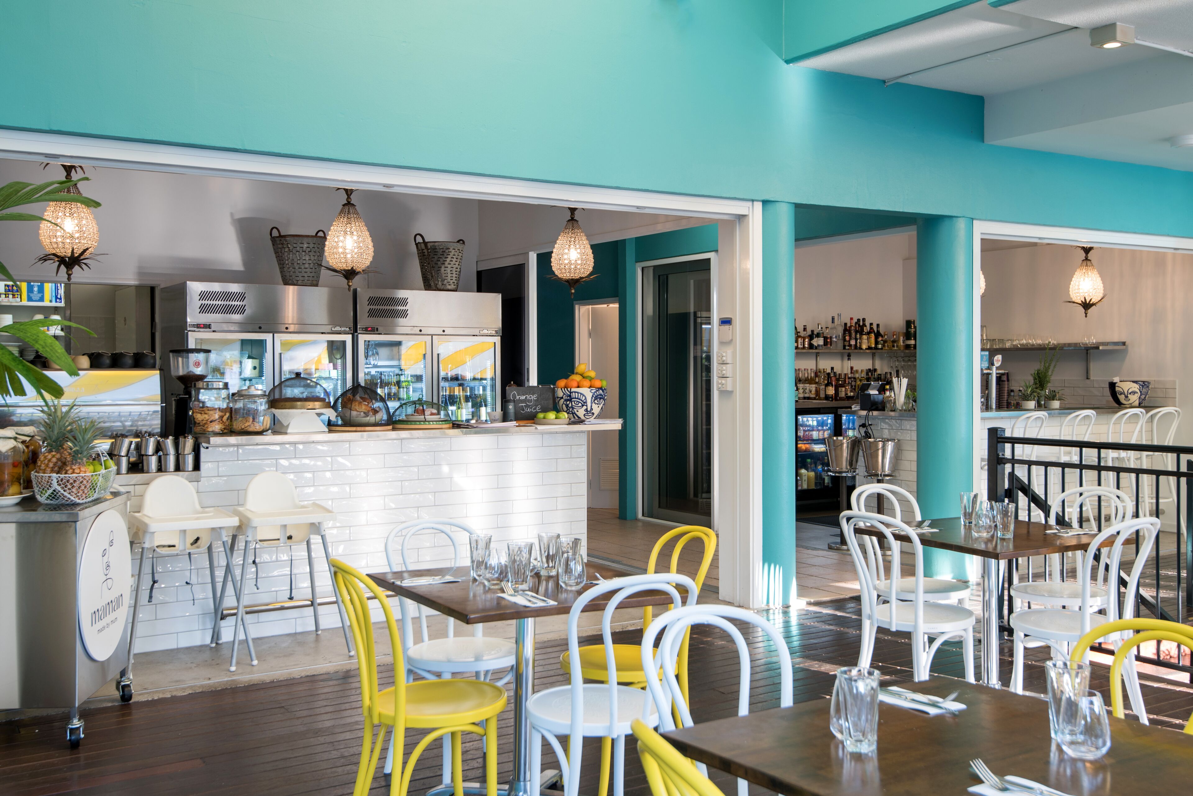 Ein Restaurant mit Barbereich, weißen Stühlen und einer Küche im Hintergrund.