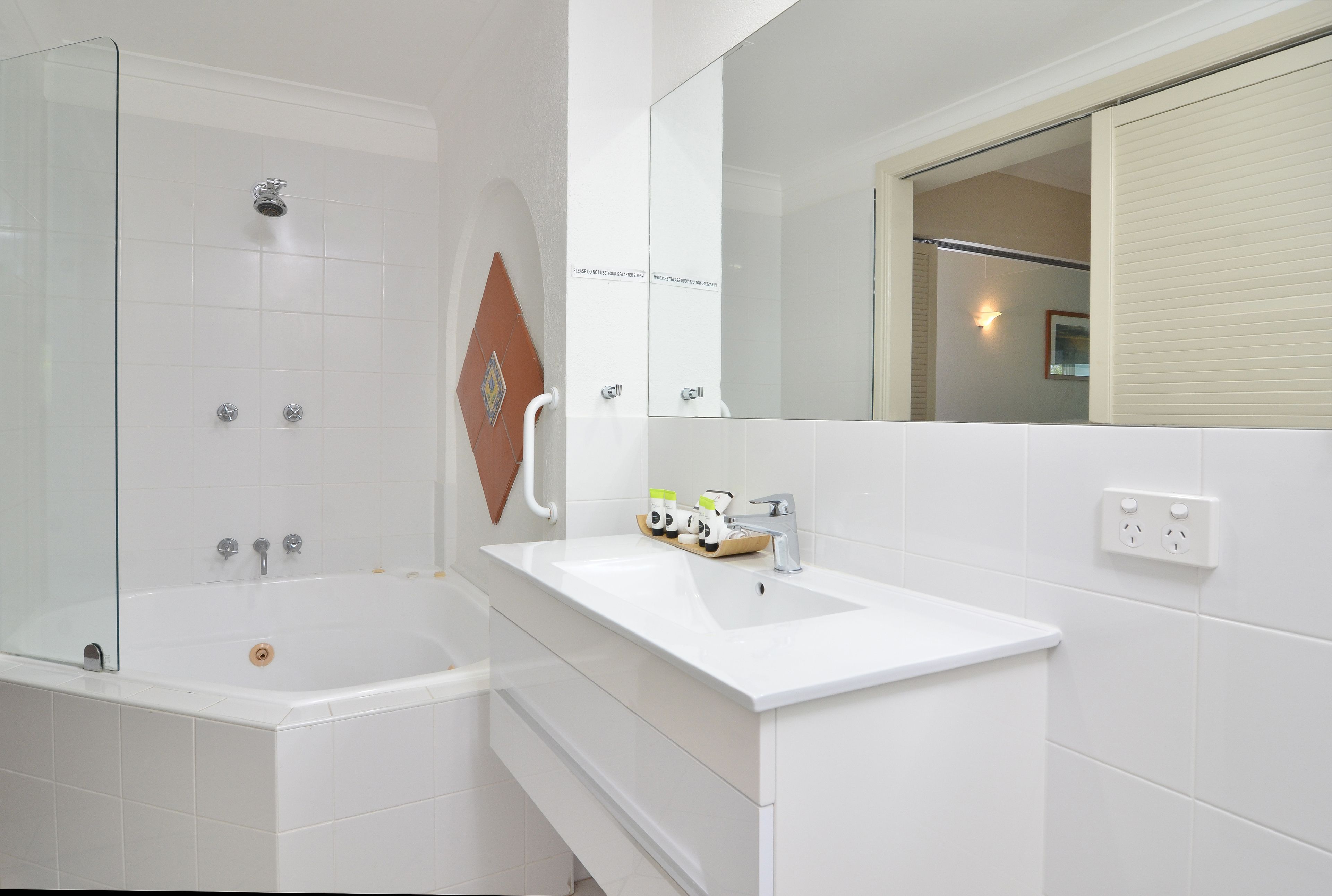 Ein modernes Badezimmer mit einer gläsernen Duschkabine, einer weißen Badewanne und einem Waschbecken mit Spiegel darüber.