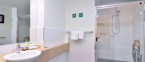 Un baño moderno con un lavabo blanco, una cabina de ducha de vidrio y un espejo.