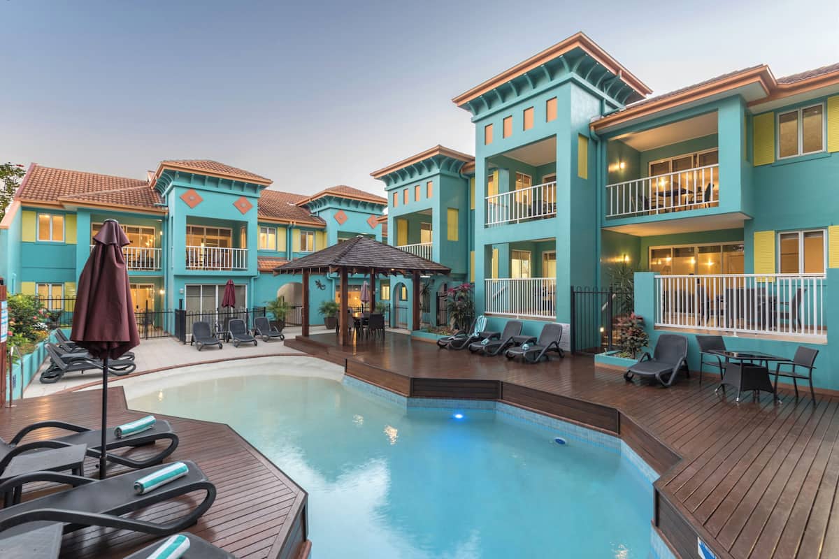 Un hotel con piscina, sillones de descanso y un patio cubierto.