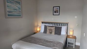 Une chambre à coucher avec un lit, des lampes de chevet, un luminaire au plafond et un tableau encadré au mur.