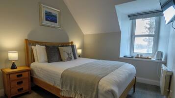 A neatly made bed with a wooden headboard, a bedside lamp, and a framed picture on the wall.