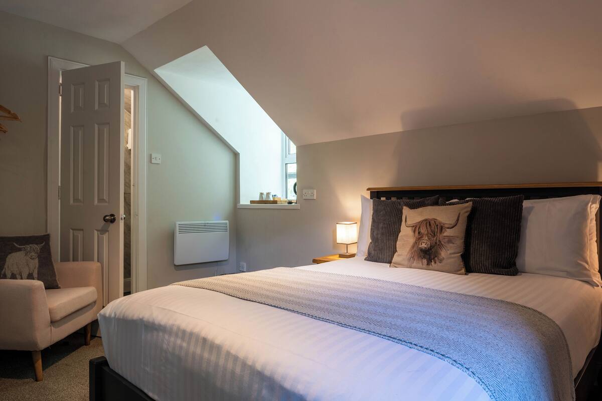 A bedroom with a bed, a chair, a window, and a skylight.