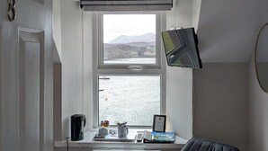 Ett rum med ett skrivbord, en stol och ett fönster med utsikt över en vattenyta.