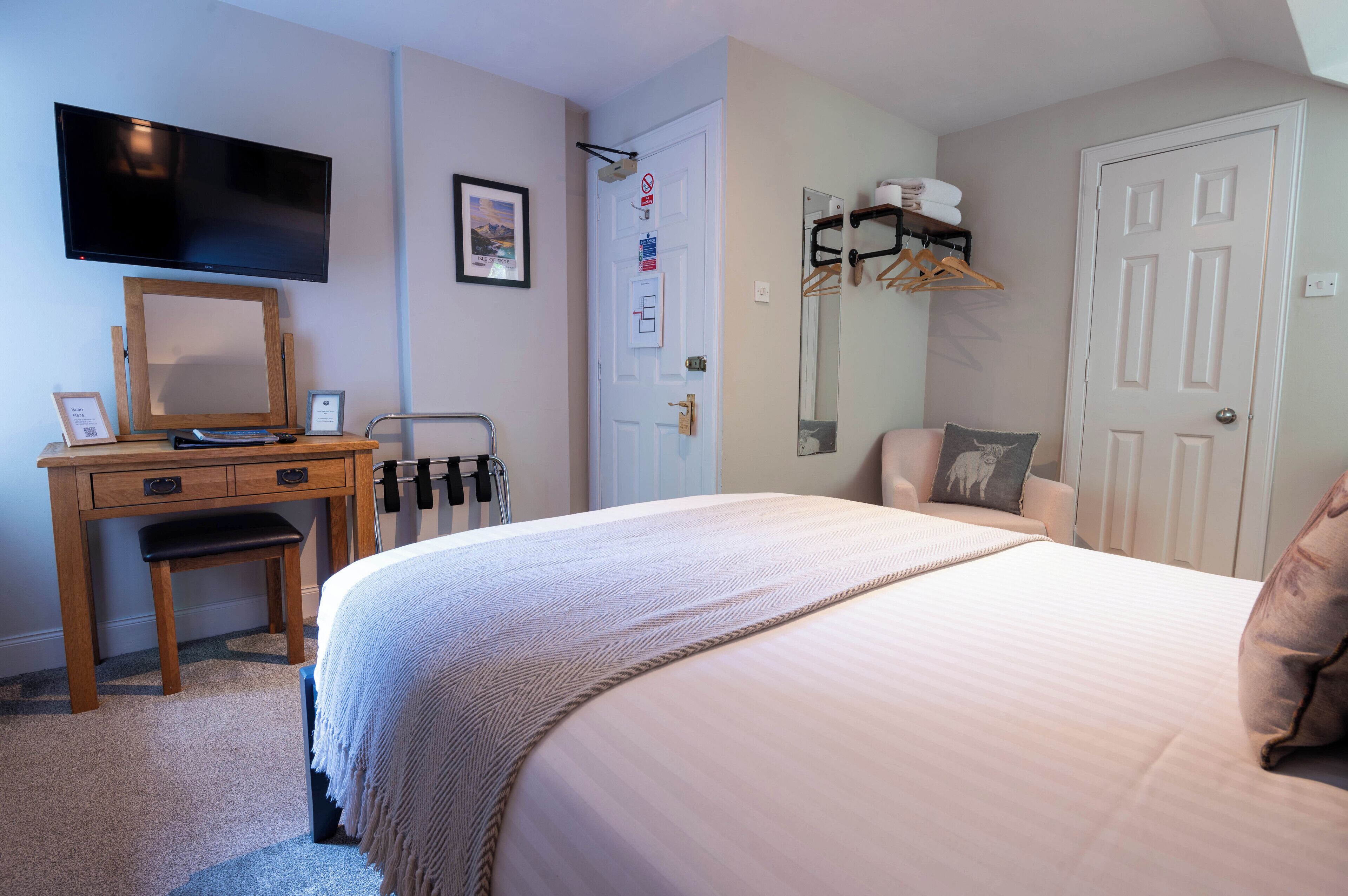 A bedroom with a bed, a desk, a chair, a TV, and a wardrobe.