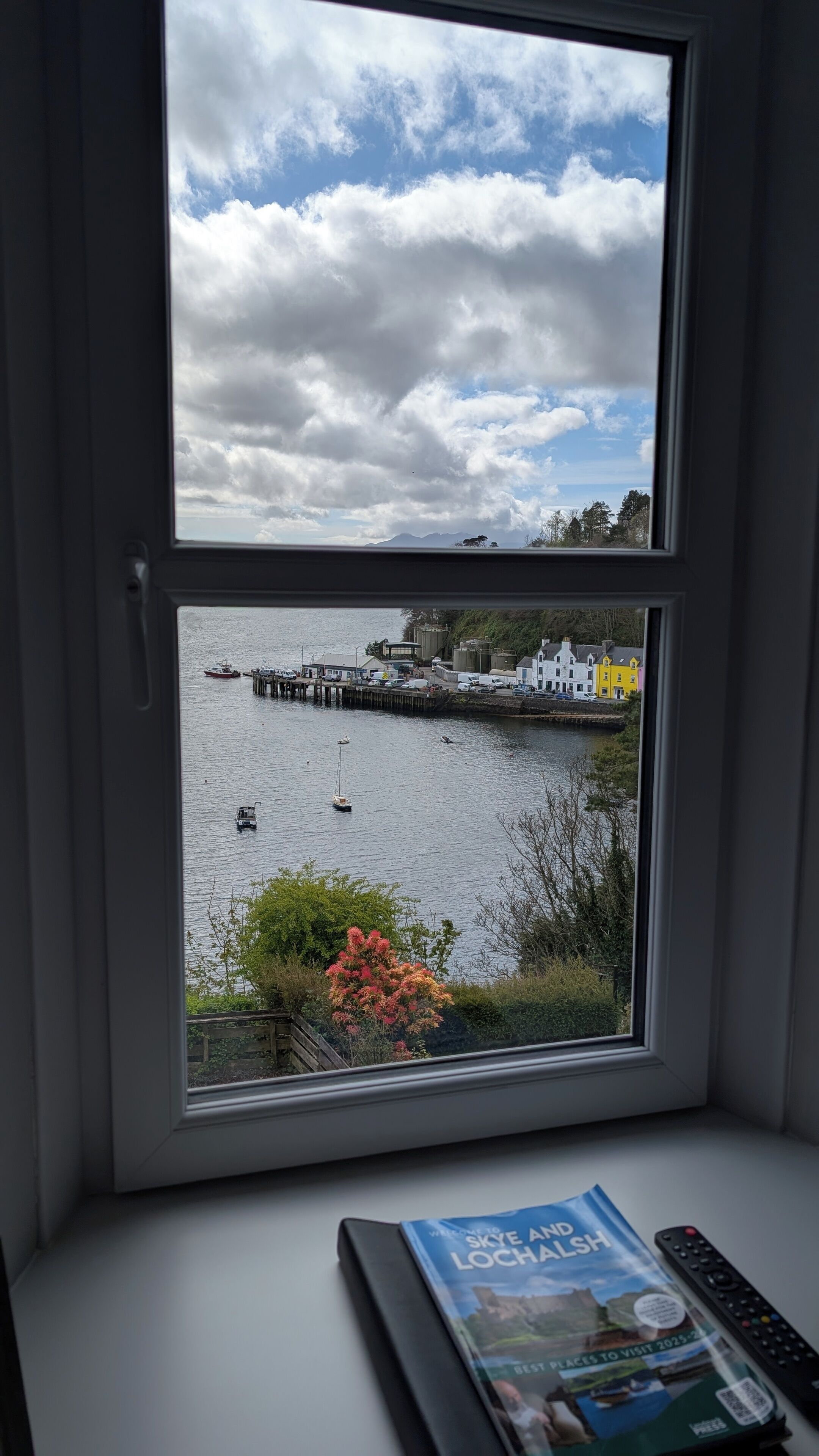 A view from a window overlooking a harbor with boats, a pier, and buildings.