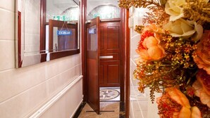 A hallway with a reception desk, a fire exit sign, and a decorative floral arrangement. - City Inn Russell Square (London)