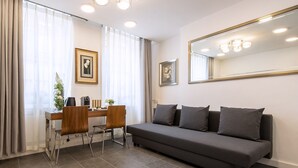 A modern living room with a sofa, a dining table with chairs, and a large mirror on the wall. - City Inn Russell Square (London)