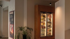 Un intérieur moderne avec un grand réfrigérateur à cadre en bois rempli de boissons, une plante en pot et une affiche accrochée au mur.