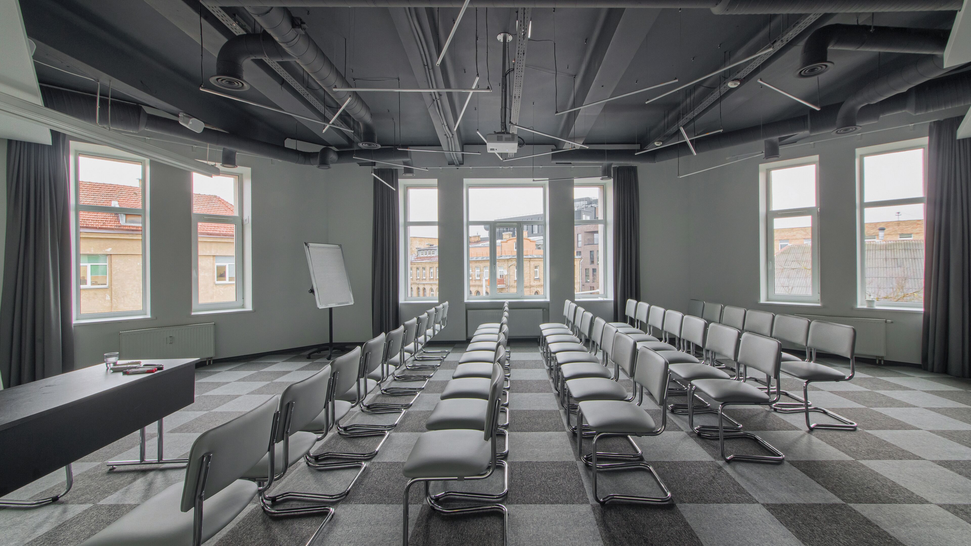 A conference room with a long table, rows of chairs, large windows, and a whiteboard.