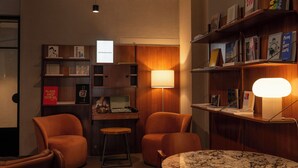 Un racó agradable per llegir amb butaques de cuir, una taula rodona petita i una prestatgeria plena de llibres i un ordinador portàtil.