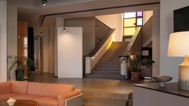 Un interior modern amb una escala, un sofà i una làmpada.